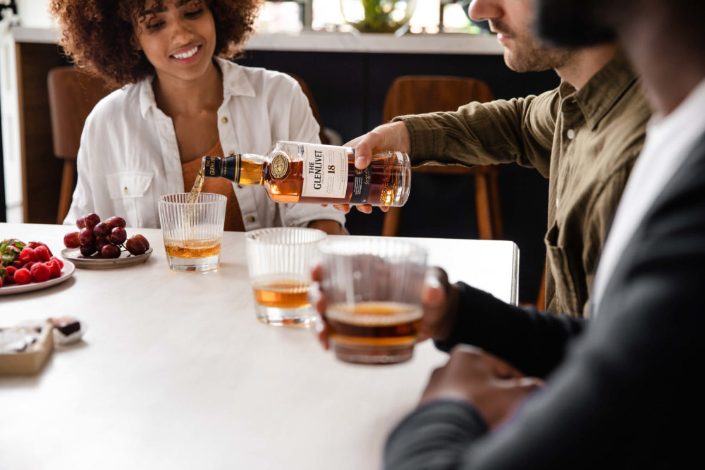 A woman smiles as she is poured a glass of Glenlivet